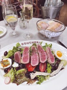 Seared tuna niçoise-style salad at Boucherie West Village, with olives, radish, soft-boiled egg and a glass of Champagne