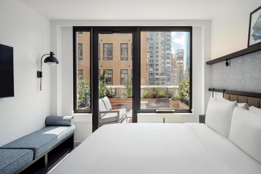 Bright hotel room at Arlo Midtown near Times Square, with a king bed, floor-to-ceiling windows and a private terrace overlooking Manhattan buildings