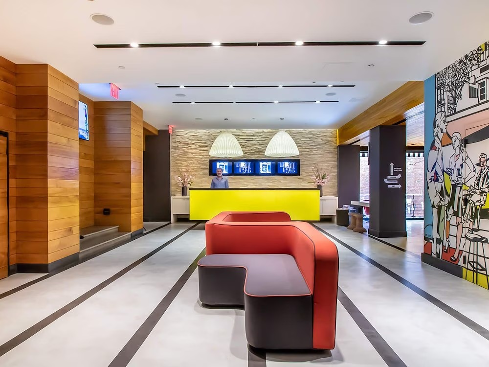 Colourful lobby at Pod 51 in Midtown Manhattan, with a yellow reception desk, a red curved sofa and a pop-art mural