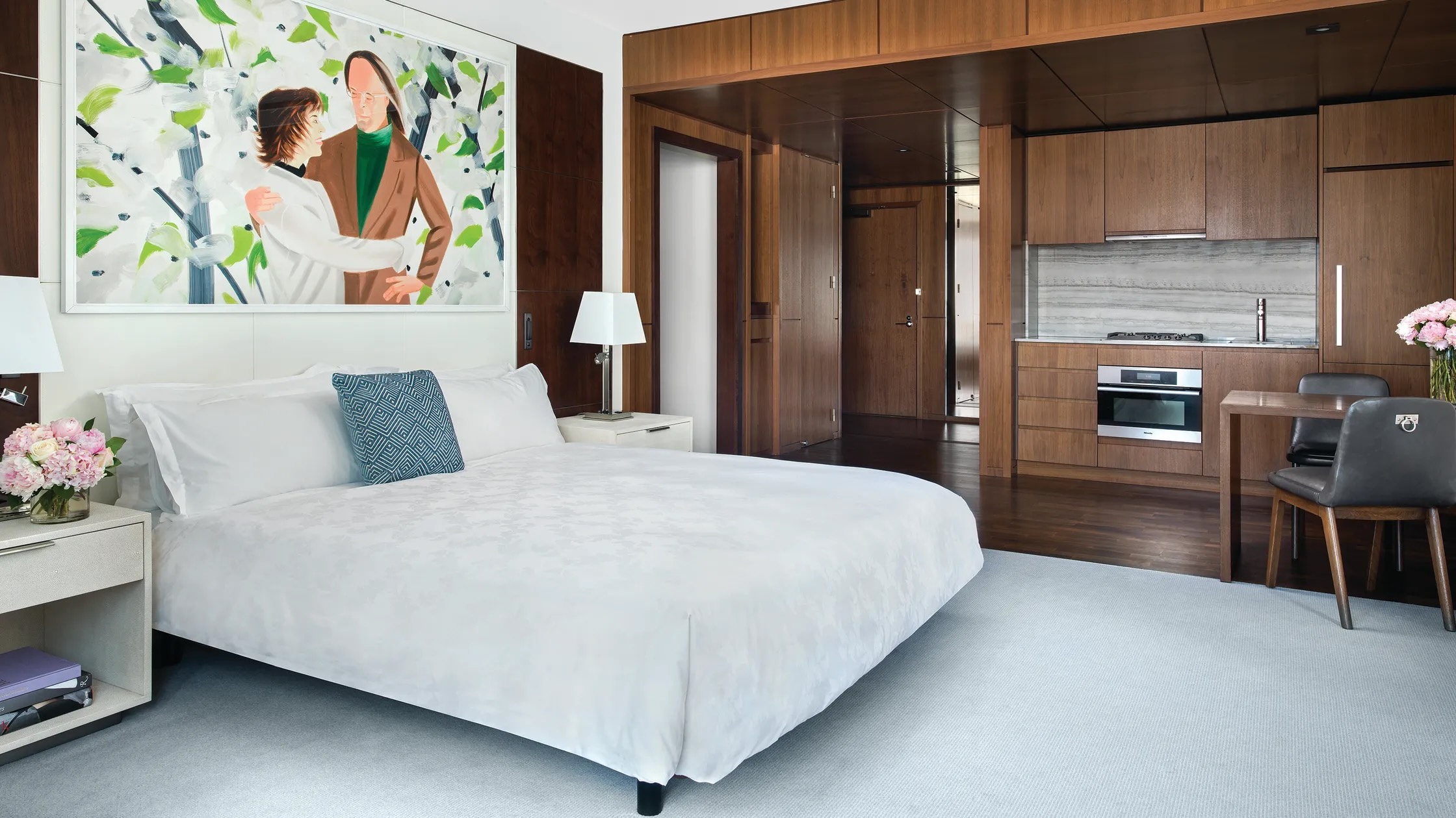 Spacious room at the Langham, New York, Fifth Avenue, with a king bed, a large colourful modern painting, walnut panelling and a kitchenette