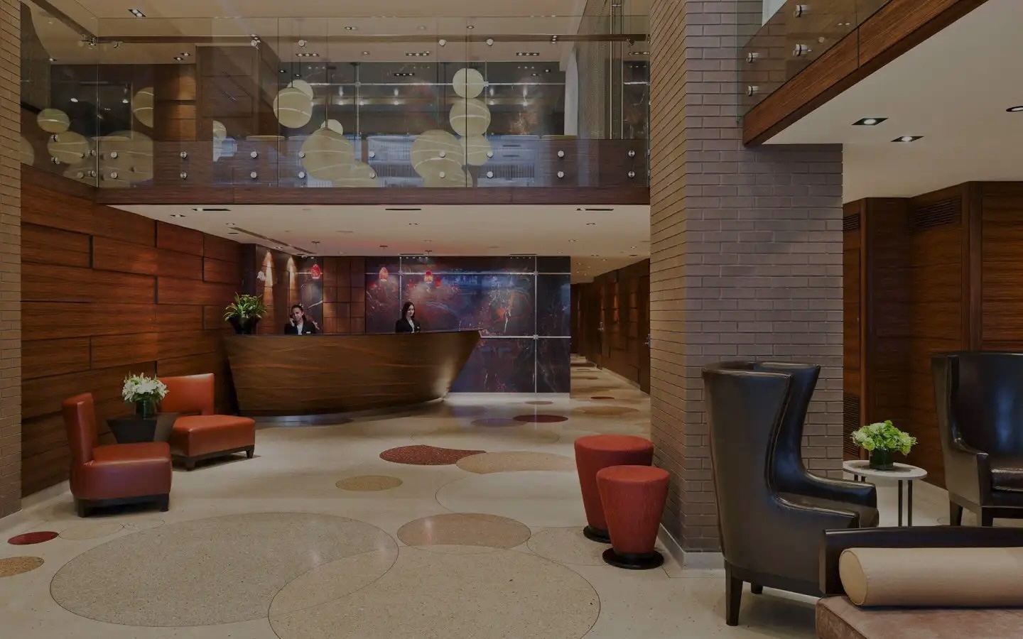 Lobby at The Pearl hotel near Times Square, with a curved wooden reception desk, terrazzo floors and orange leather armchairs